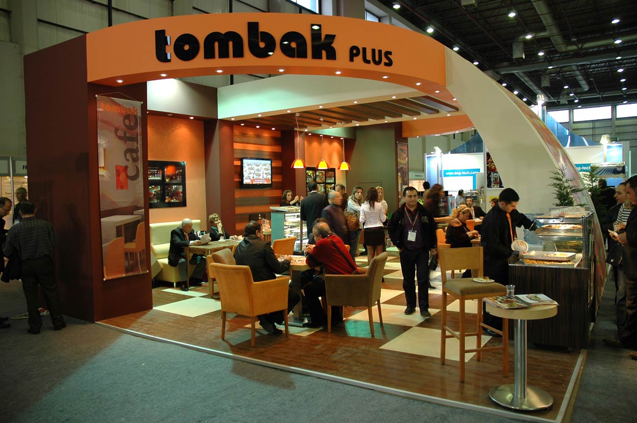 Crowded people sitting at the seating area of Tombak plus orange large Trade Stand..
