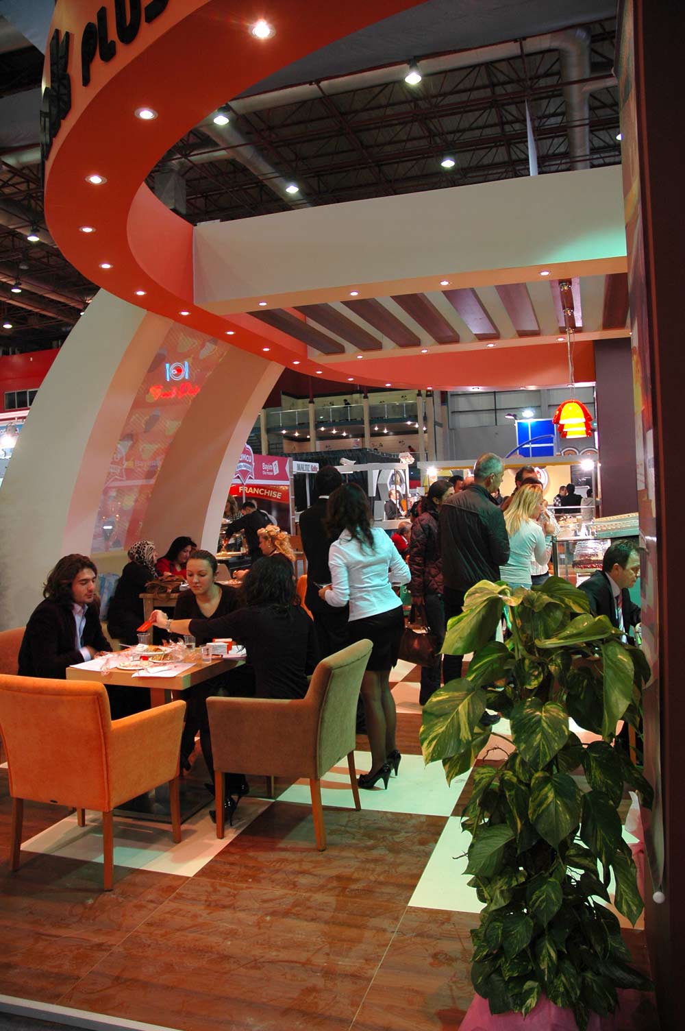 Seating area with people sitting and eating sweets in an orange Trade Stand.