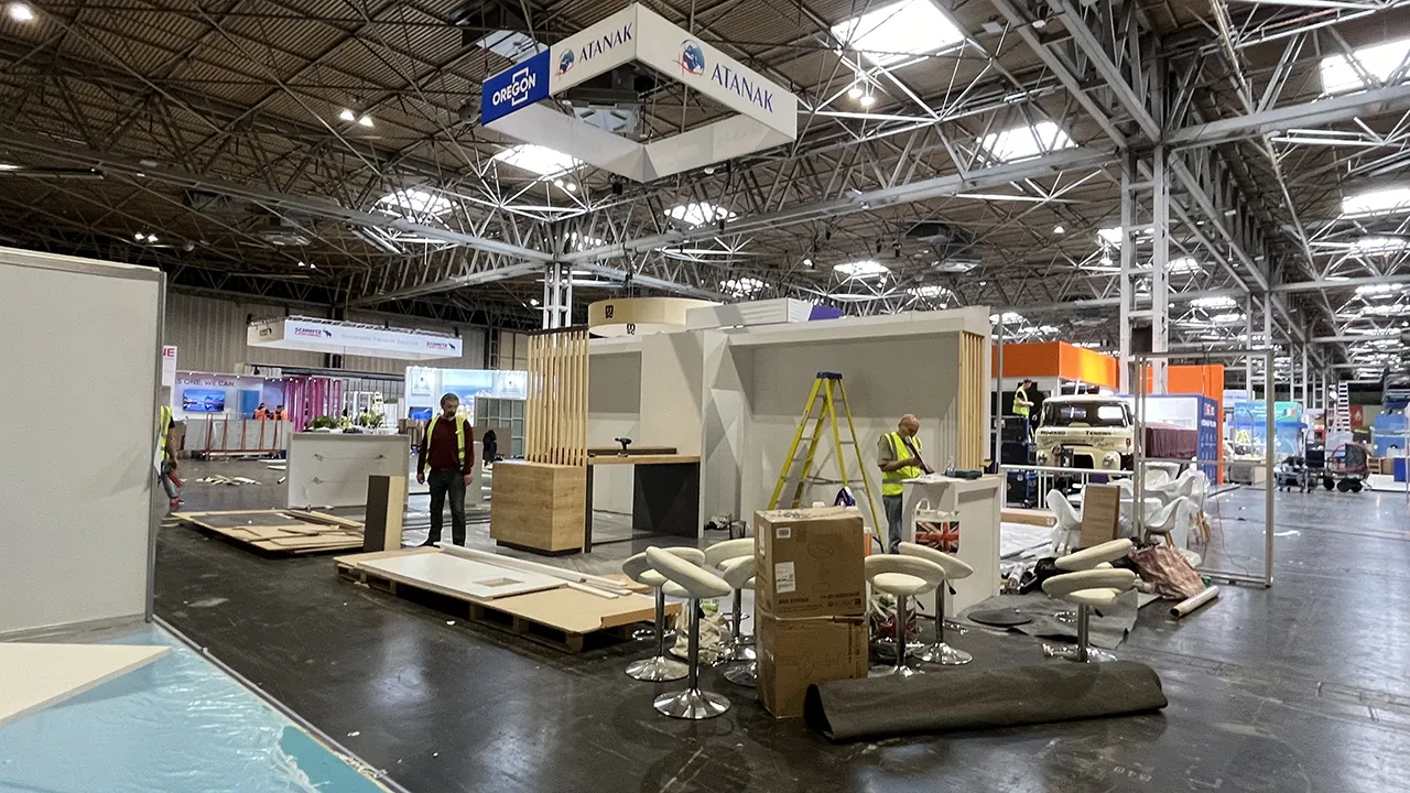 Two men working inside aw white Exhibition Booth made of wood