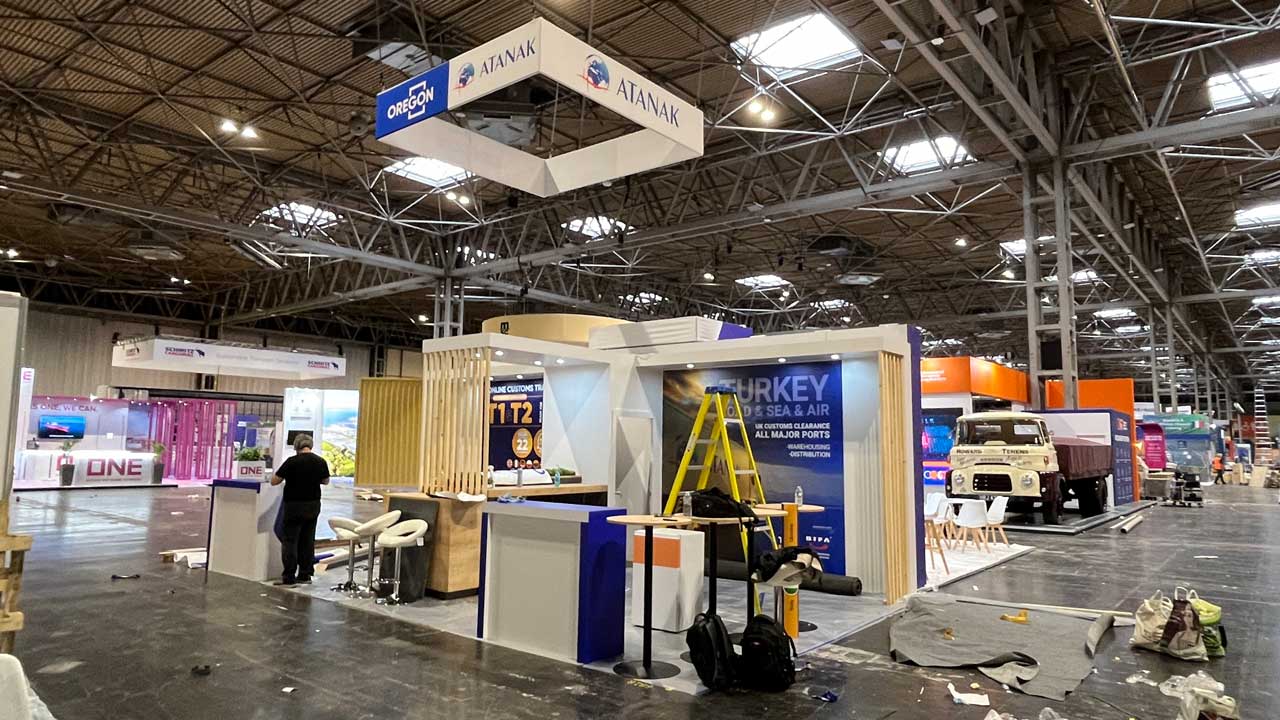 White and blue Modern Trade Stand construction that has a yellow ladder and a man inside.