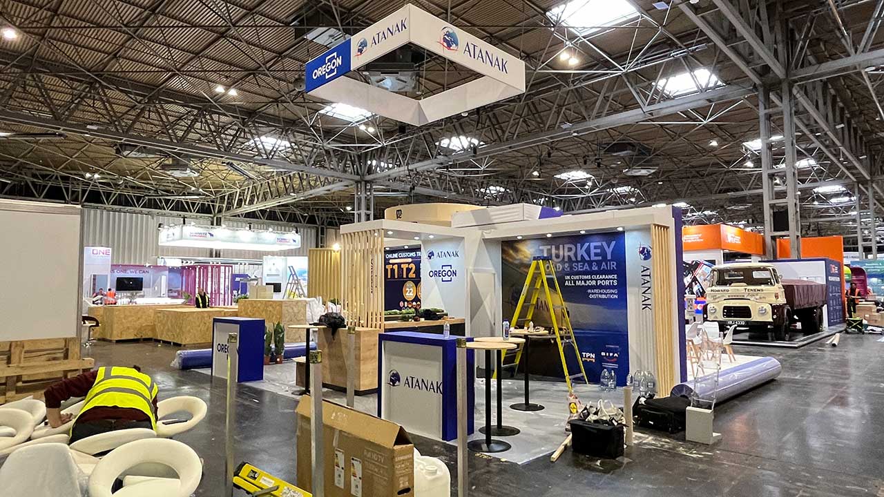 White and blue Modern Trade Stand construction that has a yellow ladder and a man inside.